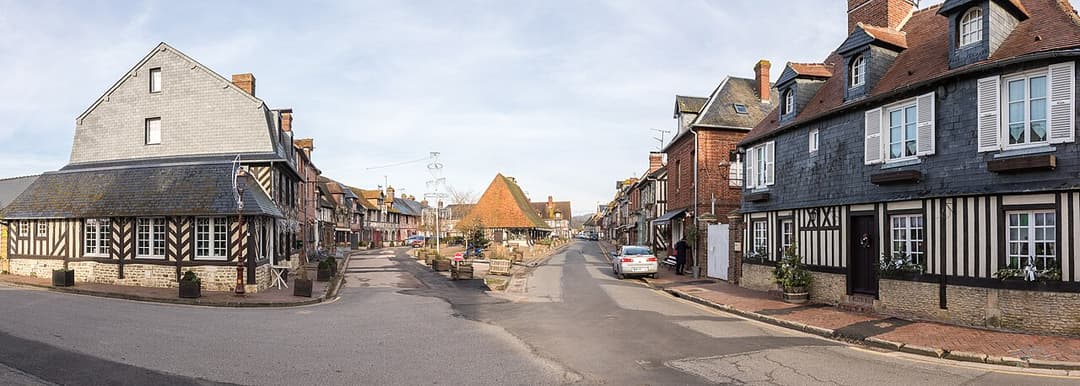 Place Michel Vermughen à Beuvron-en-Auge, bordée de maisons à colombages ; photographie d’illustration.